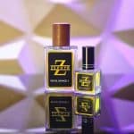 Zephyr Royal Savage Y concentrated perfume oil clear glass bottles in 30ml with wooden cap and 10ml with black cap on a dark reflective surface.